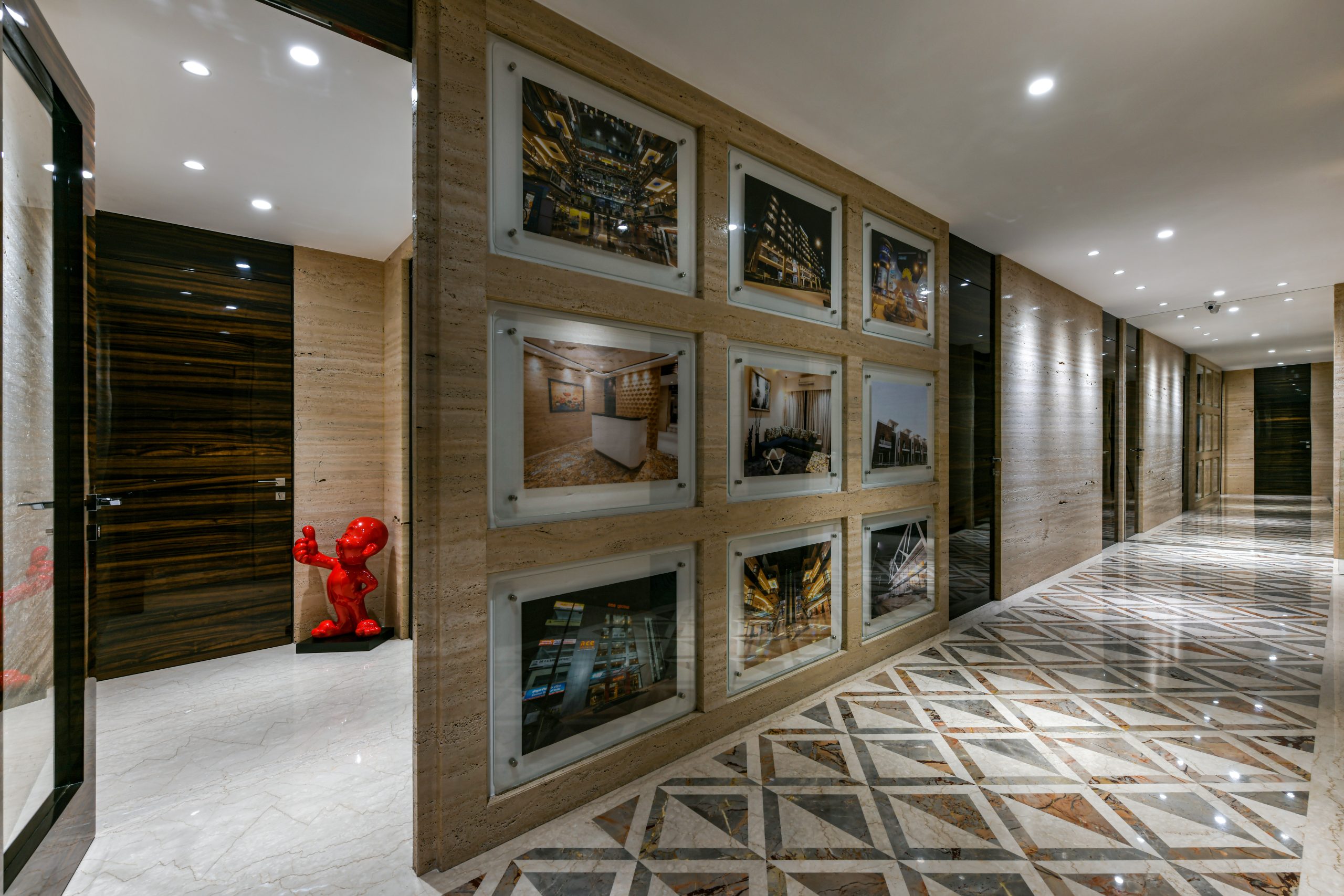 a hallway with a wall of pictures and a red teddy bear.